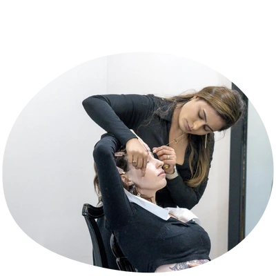 A stylist adjusts the hair of a seated client, showcasing a professional salon setting with modern decor.